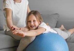 mama ayudando niña hacer ejercicio pelota