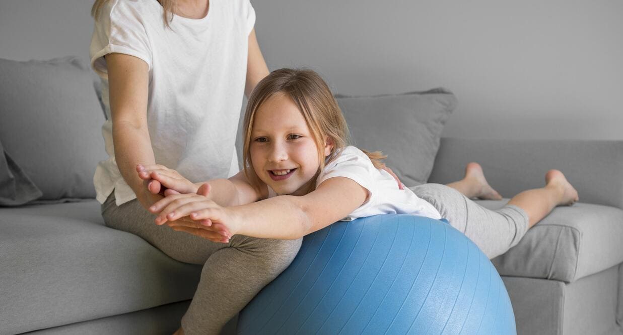 mama ayudando niña hacer ejercicio pelota